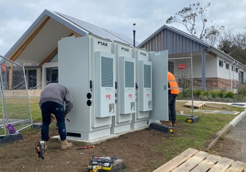 Two men installing a battery for a solar PV system